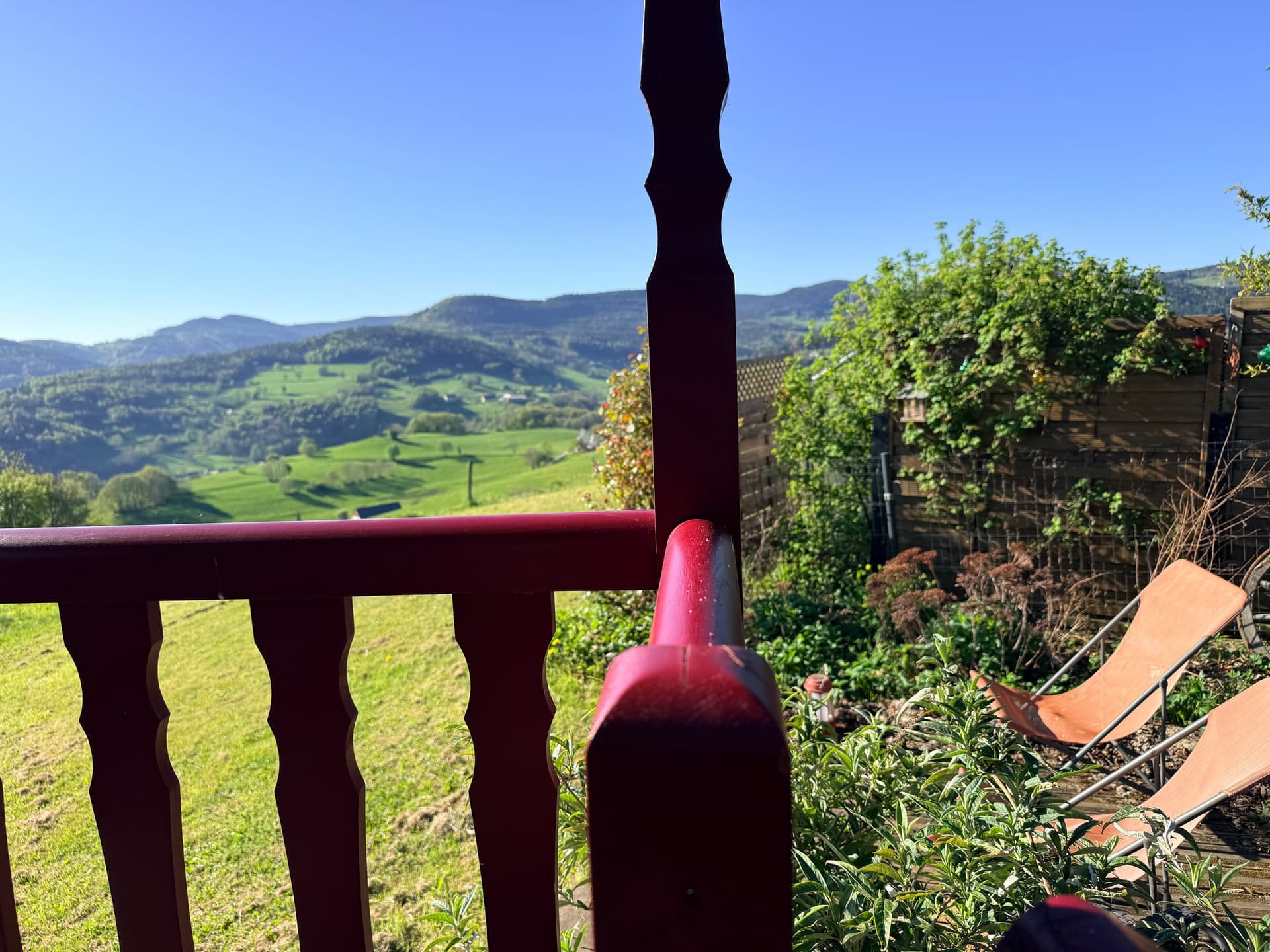 Poteau de la terrasse en bois, vue sur les prés en arrière-plan.